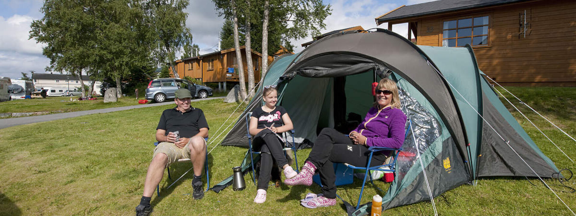 Folk som sitter ved et telt på en campingplass